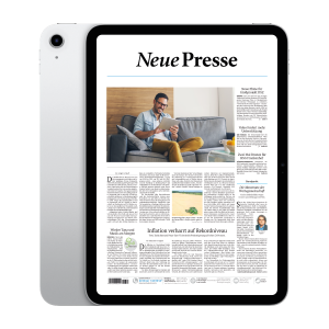 Tablet displaying a newspaper layout 'Neue Presse' on a living room sofa, man reading on a tablet beside cushions.